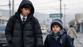Adolescente y niño caminando en un clima frío por las calles de Torreón hacia la escuela.