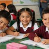 Niños de primaria en un salón de clases sonriendo a la cámara. Beca Rita Cetina.