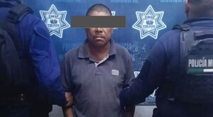 Hombre con los ojos censurados con un recuadro gris siendo detenido por dos policías municipales de Autlán