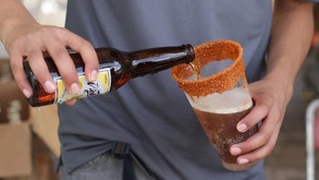 Persona sirviendo una cerveza en un vaso de plástico.