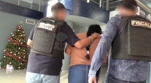 Mujer identificada como Yoana Lizbeth N vista de espaldas siendo detenida por dos policías de la Fiscalía de Jalisco