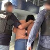 Mujer identificada como Yoana Lizbeth N vista de espaldas siendo detenida por dos policías de la Fiscalía de Jalisco