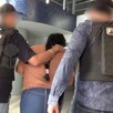 Mujer identificada como Yoana Lizbeth N vista de espaldas siendo detenida por dos policías de la Fiscalía de Jalisco