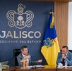 El gobernador Pablo Lemus encabeza una reunión de gabinete frente al logotipo del Gobierno de Jalisco, flanqueado por las banderas de México y del estado.