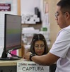 Hombre parado frente a una computadora mientras responde su examen teórico para tramitar la licencia de conducir en Puebla.