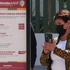 Mujer con celular en la mano frente a un anuncio de parquímetros en Puebla.