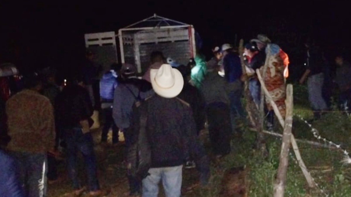 Hombre con sombrero se une a una multitud entre la oscuridad.