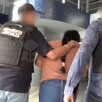 Mujer identificada como Yoana Lizbeth N vista de espaldas siendo detenida por dos policías de la Fiscalía de Jalisco