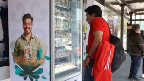 Persona parada frente a una máquina expendedora de snacks en una línea de RUTA en Puebla.