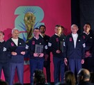 Un grupo de hombres con chamarras deportivas negras posa frente a un logo de la Copa Mundial de la FIFA 2026 durante un evento de presentación.