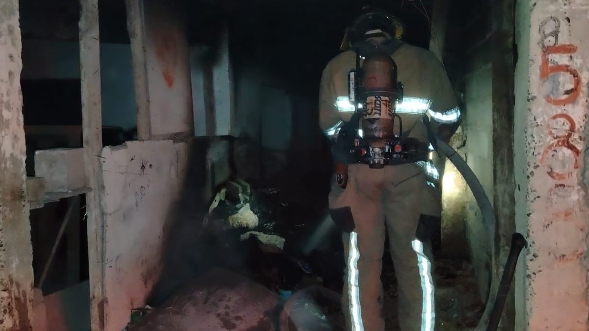 Bombero con manguera terminando con el fuego tras incendio.