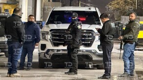 Se observan varias personas con uniforme negro en medio de una calle y un vehículo a lado.