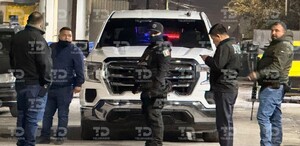 Se observan varias personas con uniforme negro en medio de una calle y un vehículo a lado.