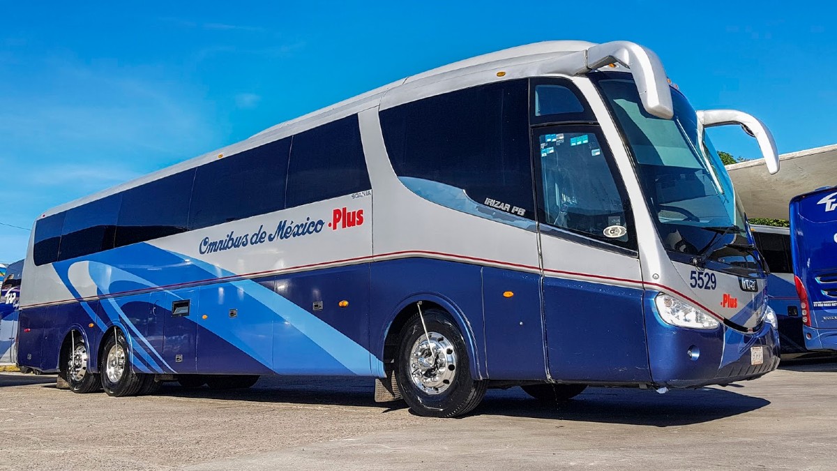 Camión color azul de Omnibus  dentro de una terminal con camiones de fondo estacionados en andenes