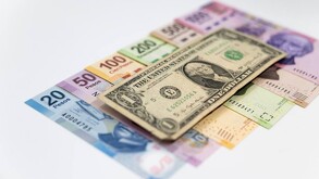 Dólar estadounidense sobre una cama de billetes de pesos mexicanos.