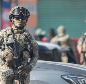 Militar armado aguarda durante un cateo realizado a la calle 46 Poniente en Puebla capital.