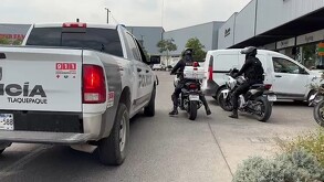 Policías a bordo de motocicletas al lado de una patrulla de la Policía de Tlaquepaque afuera de una plaza comercial