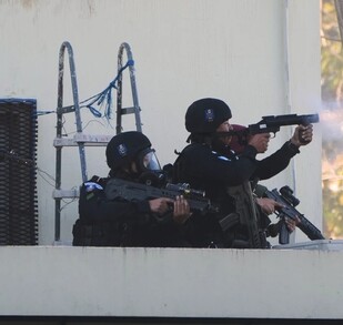 Policías y militares de Guatemala en el techado de una prisión disparando con armas largas