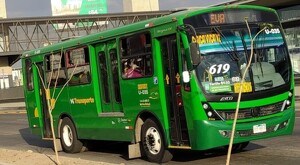 Camión verde de la ruta 619 transitando durante el día por calles de Tlajomulco con un puente peatonal detrás