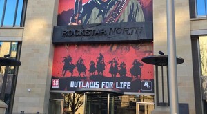Vista de la fachada principal del edificio de Rockstar North con carteles del videojuego Red Dead Redemption