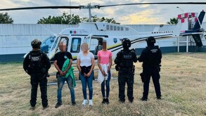 Tres personas detenidas con rostros pixelados aparecen frente a un helicóptero ambulancia, custodiadas por agentes de la SSPC y la Guardia Civil.