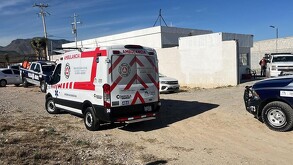 Se observa una ambulancia de color blanco, hay otros vehículos estacionados.