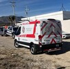 Se observa una ambulancia de color blanco, hay otros vehículos estacionados.