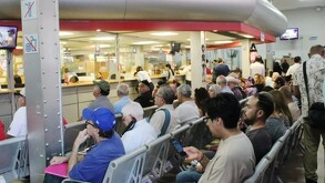 Una persona sostiene un par de placas de circulación de Jalisco nuevas, frente a una caja de cartón abierta que contiene muchos más juegos de placas.
