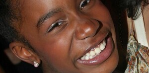 Joven mujer sonriendo a la cámara con aretes redondos en color rosa