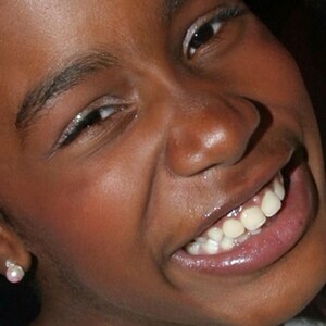 Joven mujer sonriendo a la cámara con aretes redondos en color rosa