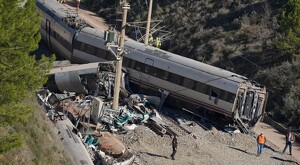 Tren volcado sobre las vías ferroviarias con restos de la maquinaria esparcidas y autoridades de España realizando labores alrededor