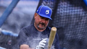 Benjamín Gil, mánager de los Charros de Jalisco, observa con atención un bate de béisbol mientras una nube de polvo de resina flota a su alrededor.