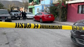 Se observa una cinta amarilla de precaución, unos carros negros y uno rojo estacionados.