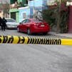 Se observa una cinta amarilla de precaución, unos carros negros y uno rojo estacionados.