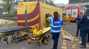 Paramédicos, policías y bomberos al lado de un camión de pasajeros volcado en su costado con camillas y camión de bomberos alrededor