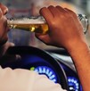 Se ve a un hombre tomando un líquido de una botella y él viste una playera blanca; está dentro de un auto.