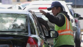 Hombre franelero habla con el conductor de un vehículo en Puebla.
