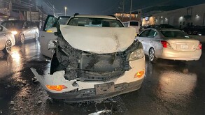 Se observa un auto destrozado del frente en color blanco, a lado se encuentra otro vehículo.