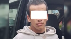 Joven identificado como Joel Martín ‘N’ con los ojos censurados por un recuadro blanco delante de una patrulla de la Policía de Guadalajara