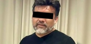 Hombre identificado como Eduardo 'N' viendo de frente con los ojos censurados delante de una cortina beige