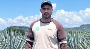 Fernando Serrano viendo de frente mientas está de pie con un campo de agave de fondo durante un día soleado