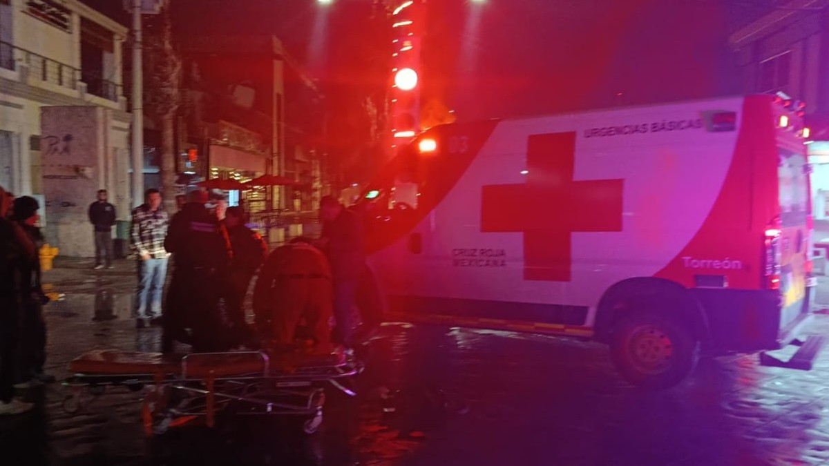 Ambulancia de Cruz Roja junto a varias personas y una camilla de paramédicos