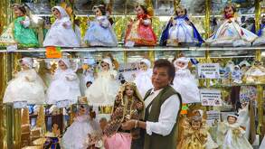 una mujer carga un niño dios en un taller de costura de vestidos de niño dios