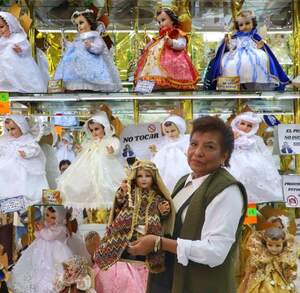 una mujer carga un niño dios en un taller de costura de vestidos de niño dios