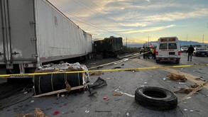 Se observa un tráiler y un carro, una llanta en la carretera y a lo lejos una ambulancia; hay una cinta amarilla de precaución.