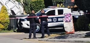 Policías junto a una patrulla municipal resguardan una zona de crimen.