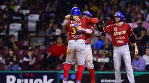 En un partido nocturno, un jugador de los Charros de Jalisco se desliza de cabeza en una base mientras el defensivo rival intenta hacer el out.