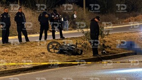 Se observan a unos policías, una cinta amarilla de precaución, una moto y un cuerpo tendido en el suelo.