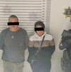 Se observa a dos personas detenidas, con cintilla negra en ojos, están detenidos.