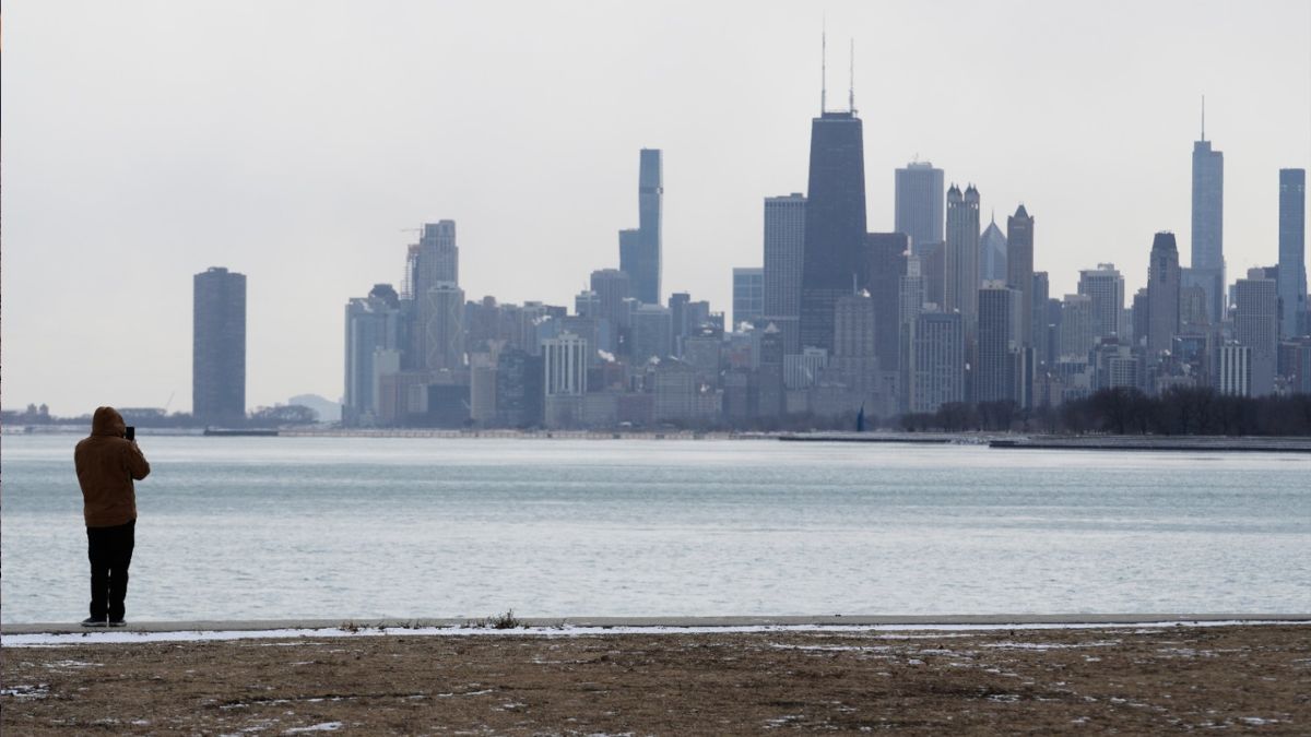Una persona se abriga bien mientras toma fotos durante un día de clima frío en el lago Michigan en Chicago